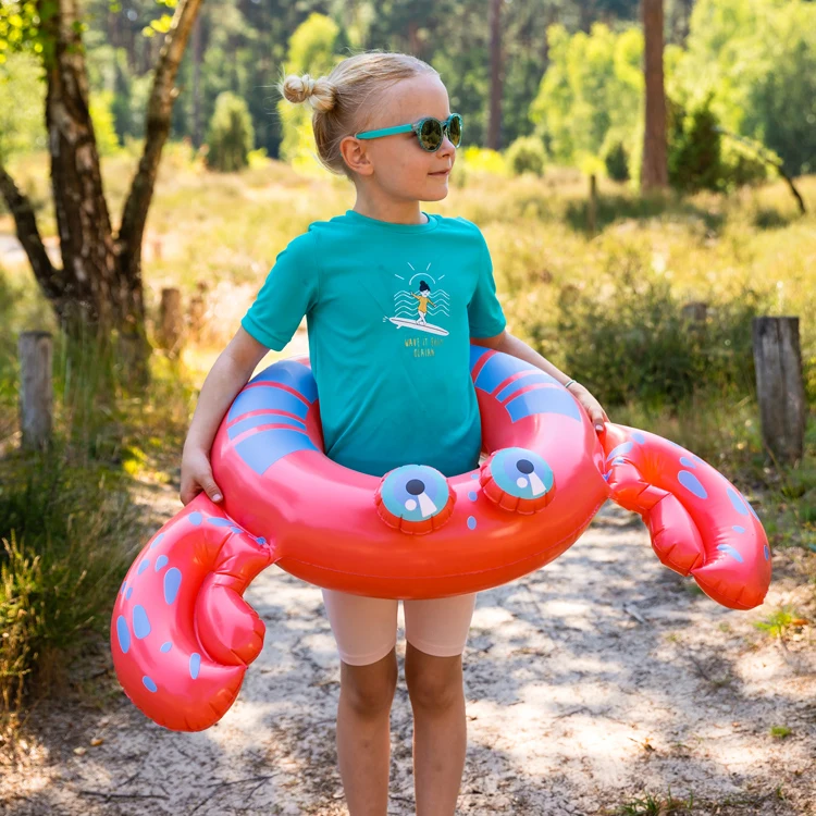 Mädchen mit Sonnenbrille, Badeanzug und Krabbenschwimmring in der Natur.