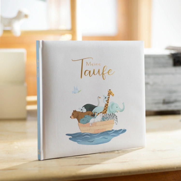 Buch mit der Aufschrift "Meine Taufe" auf einem hellen Tisch.