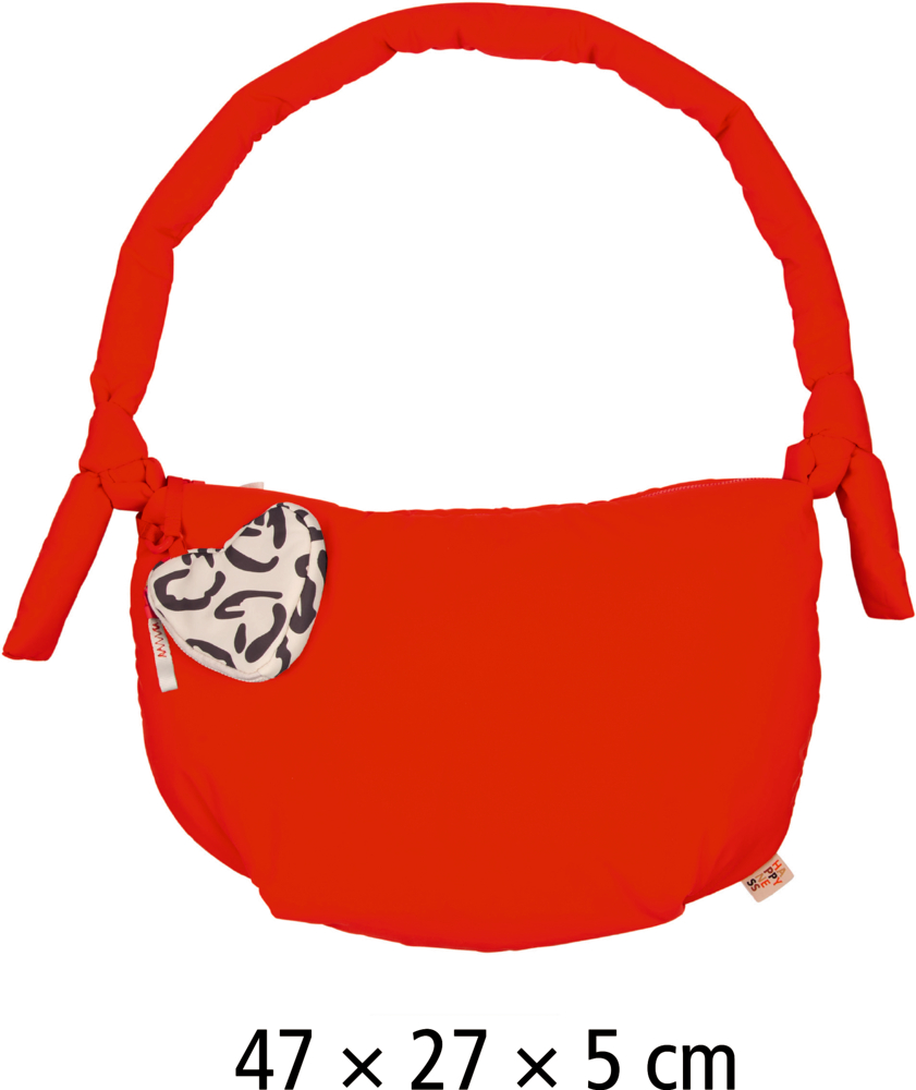 Orange Tasche mit gepolstertem Henkel, seitlichen Knoten und herzförmigem Anhänger mit schwarz-weißem Muster.