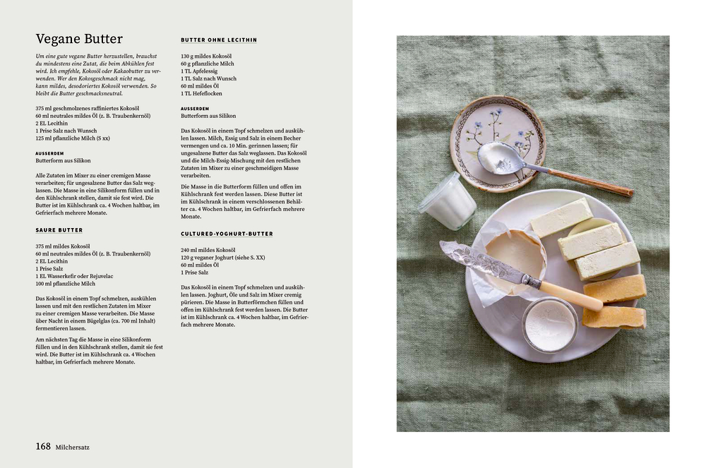 Butter, Messer, Milch, Salzschale und Untertasse mit Blumenmuster auf einem grünen Tuch angeordnet.