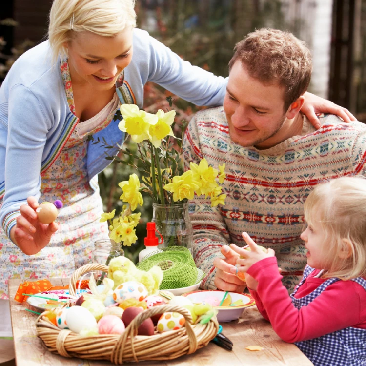 Familie draußen mit Narzissen und OSterdeko am Tisch.