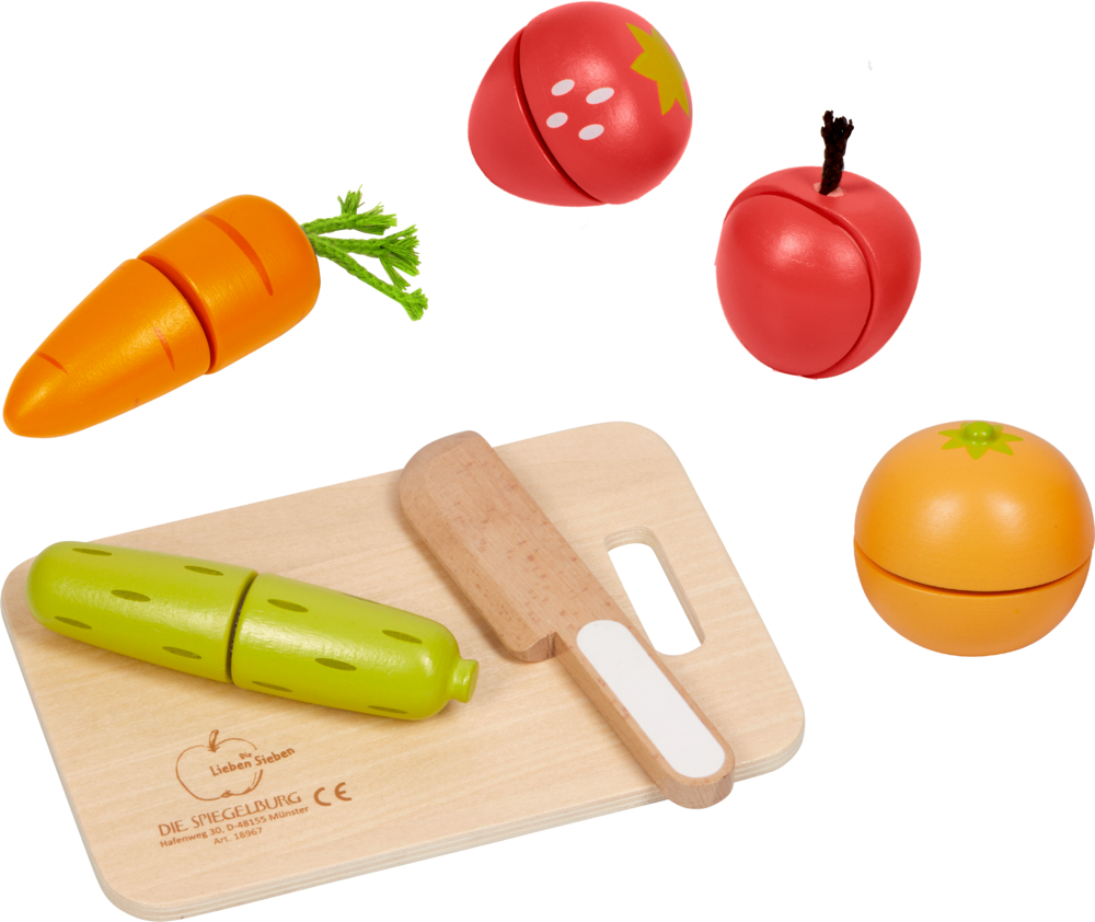 Spielzeugkarotte, -gurke, -tomate und -erdbeere mit einem Spielzeugmesser auf einem hölzernen Schneidebrett.