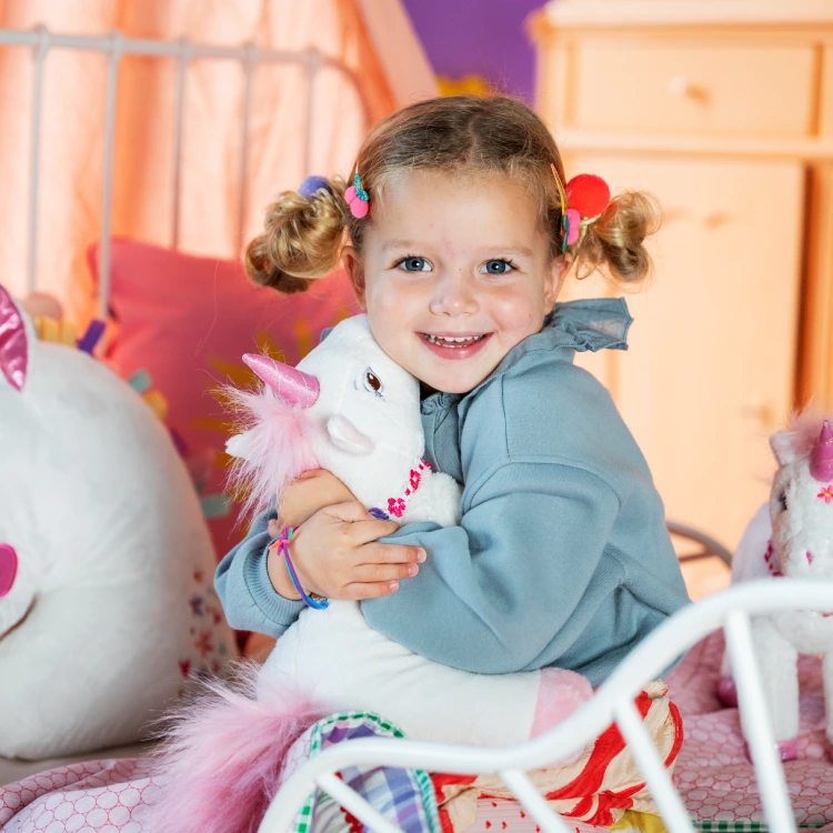 Kleines Mädchen kuschelt mit Plüsch-Einhorn