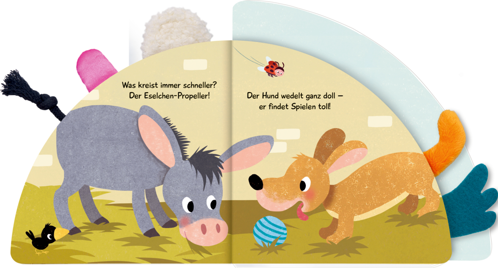 Aufgeschlagenes Bilderbuch mit gezeichnetem Esel, Hund, Vogel und Marienkäfer, dazu bunte Stoffelemente an der Seite.