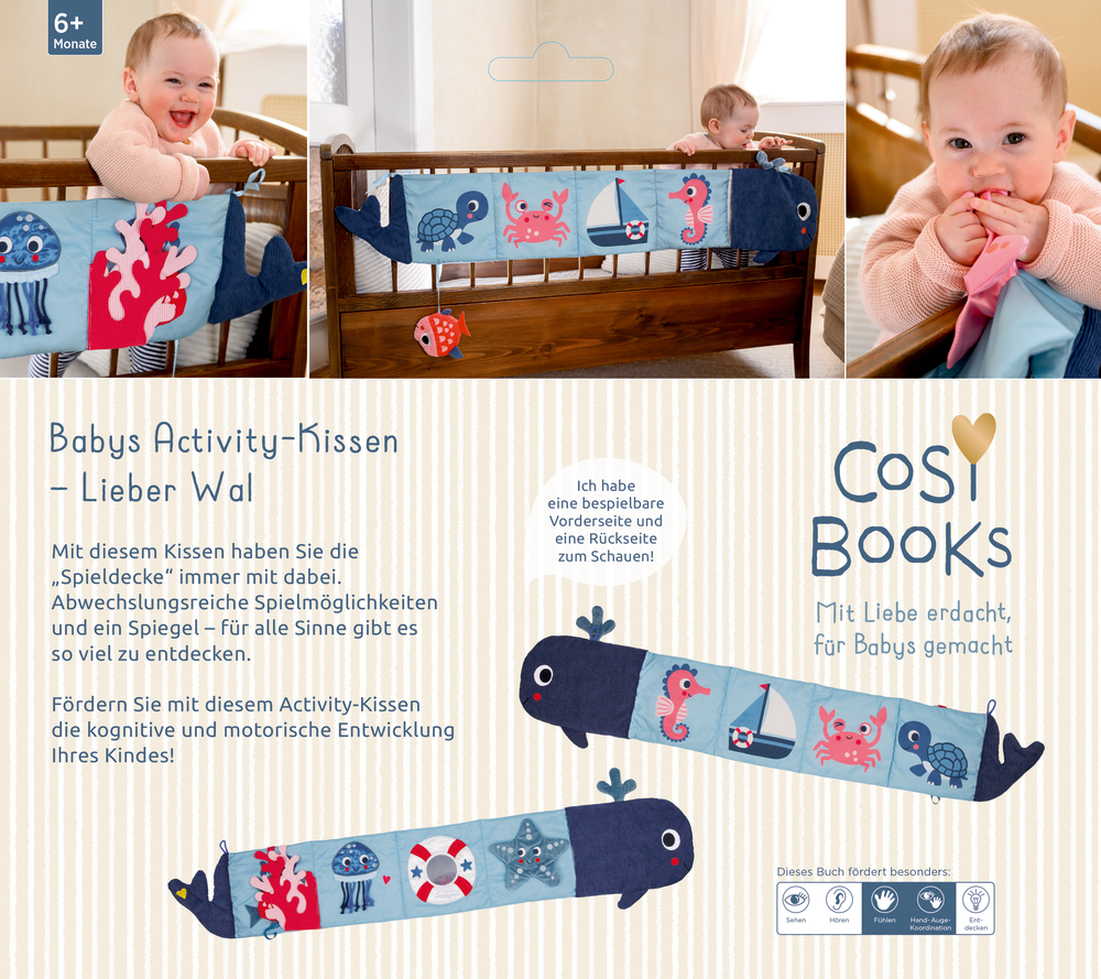Langes blaues Activity-Kissen in Walform mit maritimen Motiven wie Krabbe, Seepferdchen, Schildkröte und kleinen Stoffanhängern am Kinderbett.