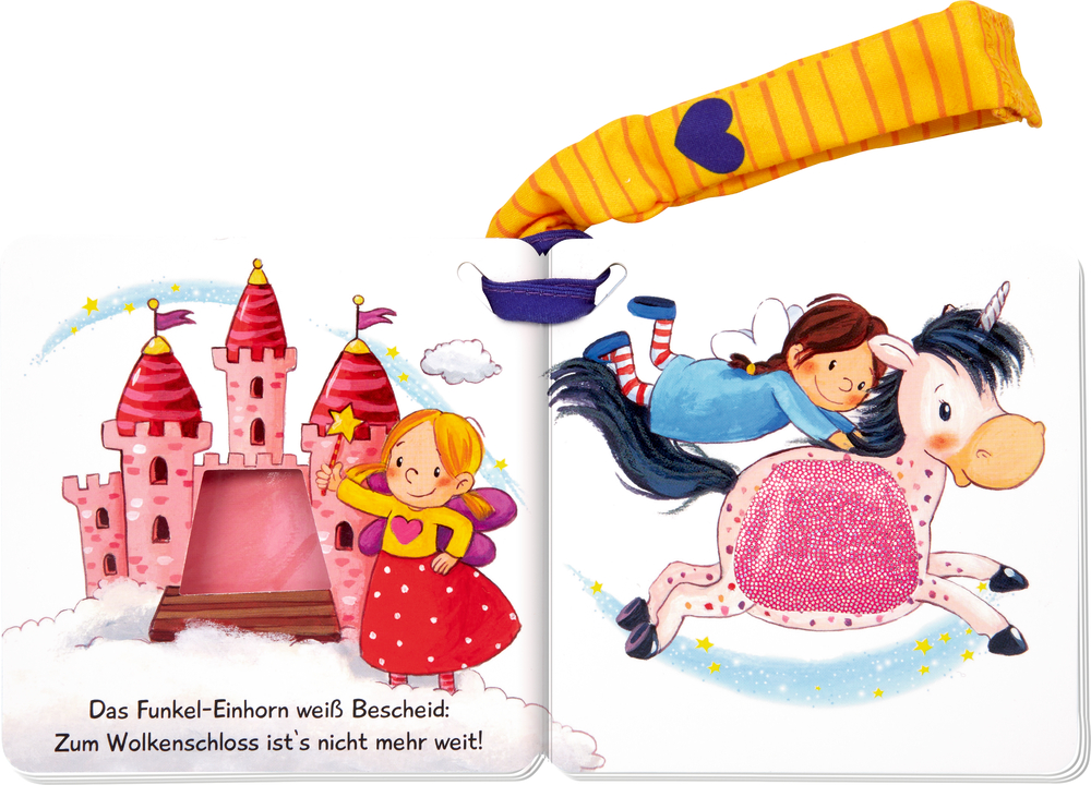 Aufgeklapptes Kinderbuch mit gezeichnetem rosa Schloss, Kind mit Zauberstab und fliegendem Einhorn mit Reiterin.