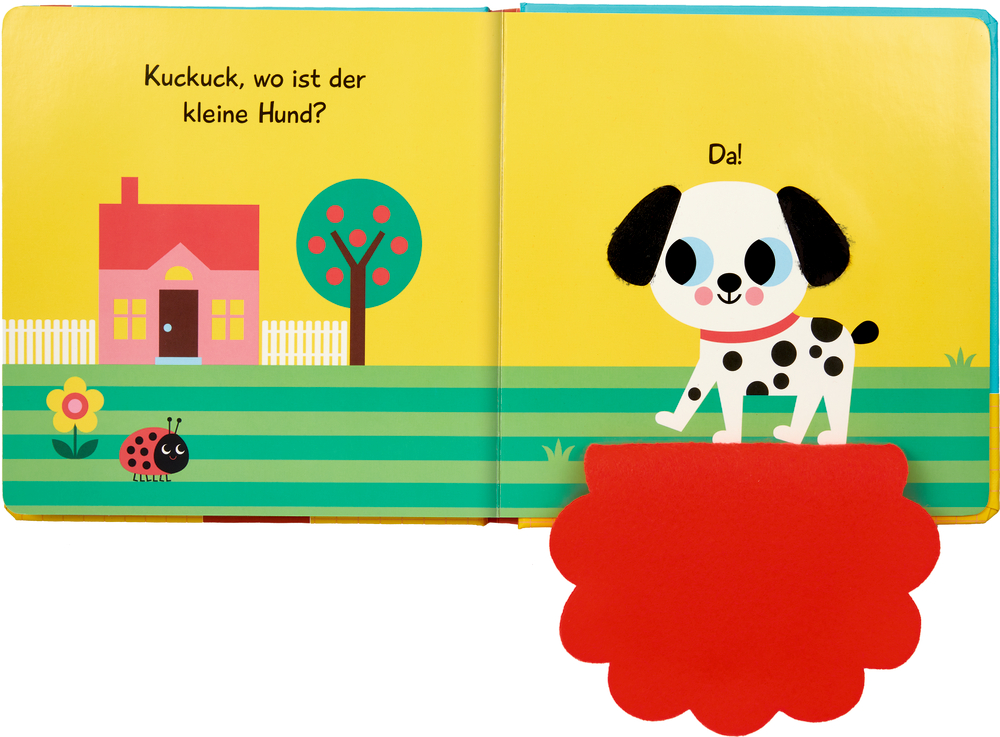 Ein gezeichneter Hund hinter einer Filzklappe steht auf Gras neben einem roten Haus, einem Baum, einer Blume und einem Marienkäfer. Darüber ist Text zu sehen.