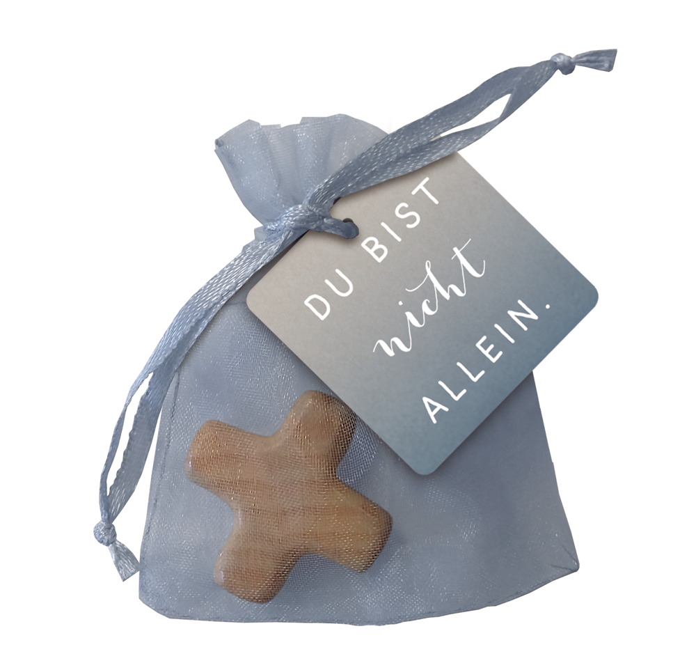 Hellblaue Geschenktüte mit einem Kreuz und einem Anhänger mit der Aufschrift „Du bist nicht allein“.