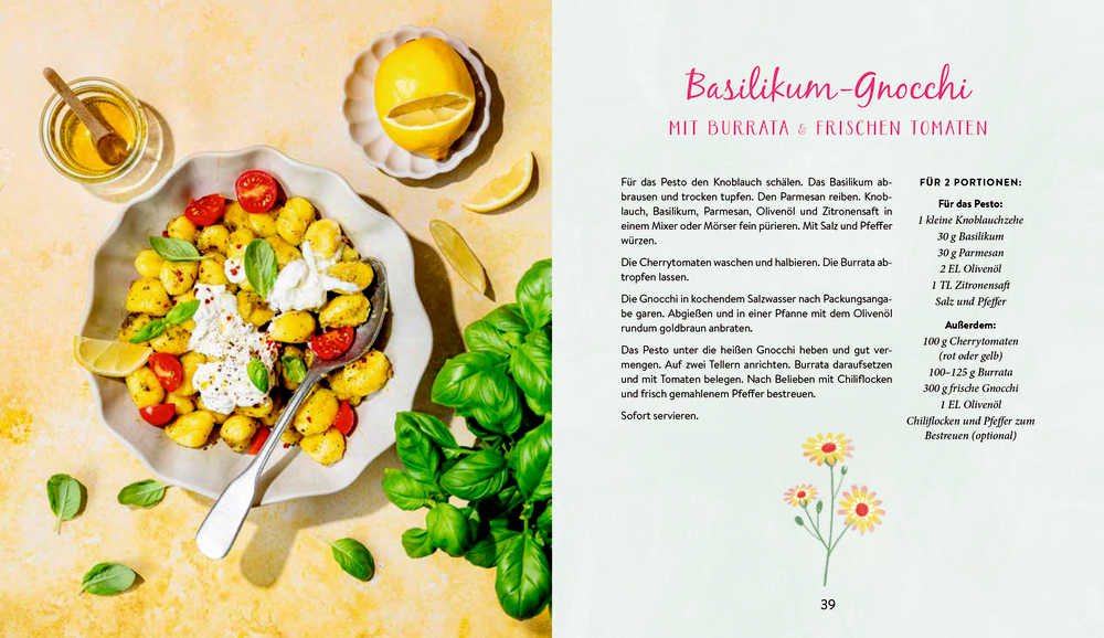 Teller mit Basilikum-Gnocchi, Burrata und Kirschtomaten. Drumherum Basilikum, Zitrone, Öl und Honig auf rosa Tisch.