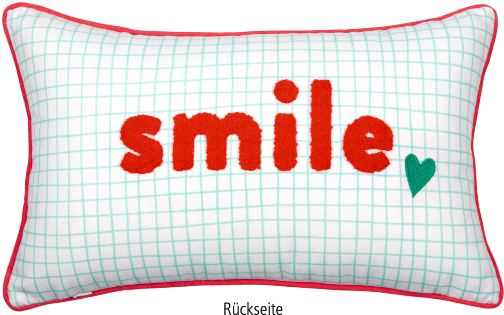 Rechteckiges Kissen mit roter Kante und türkisfarbenem Karomuster, rotem Schriftzug „smile“ aus einer punch needle Stickerei und türkisem Herzmotiv.