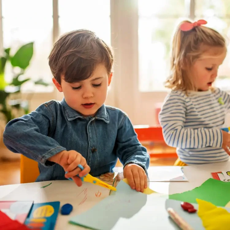 Bastelnde Kinder an einem Tisch in einem hellen Raum.