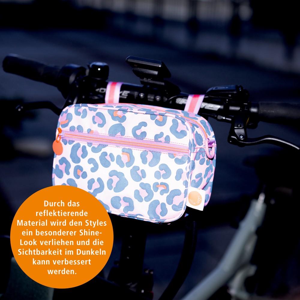 Reflektierende Lenkertasche mit Leopardenmuster befestigt am Fahrradlenker, beleuchtet in dunkler Umgebung.
