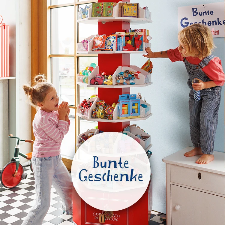 Zwei Kinder betrachten den Inhalt einer mit kleinen Spielsachen gefüllten Drehsäule.