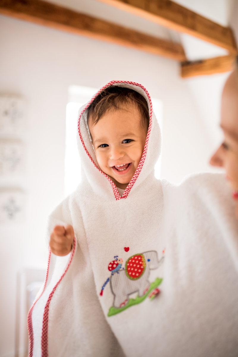 fröhlich lachendes Kind in einem weißen Badeponcho