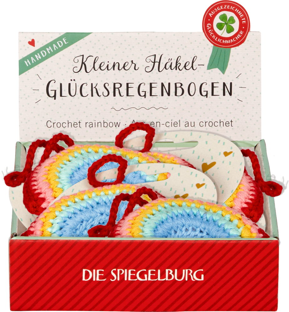 Schachtel mit bunten gehäkelten Regenbogenornamenten mit der Aufschrift „Kleiner Häkel-Glücksregenbogen“ von Die Spiegelburg.