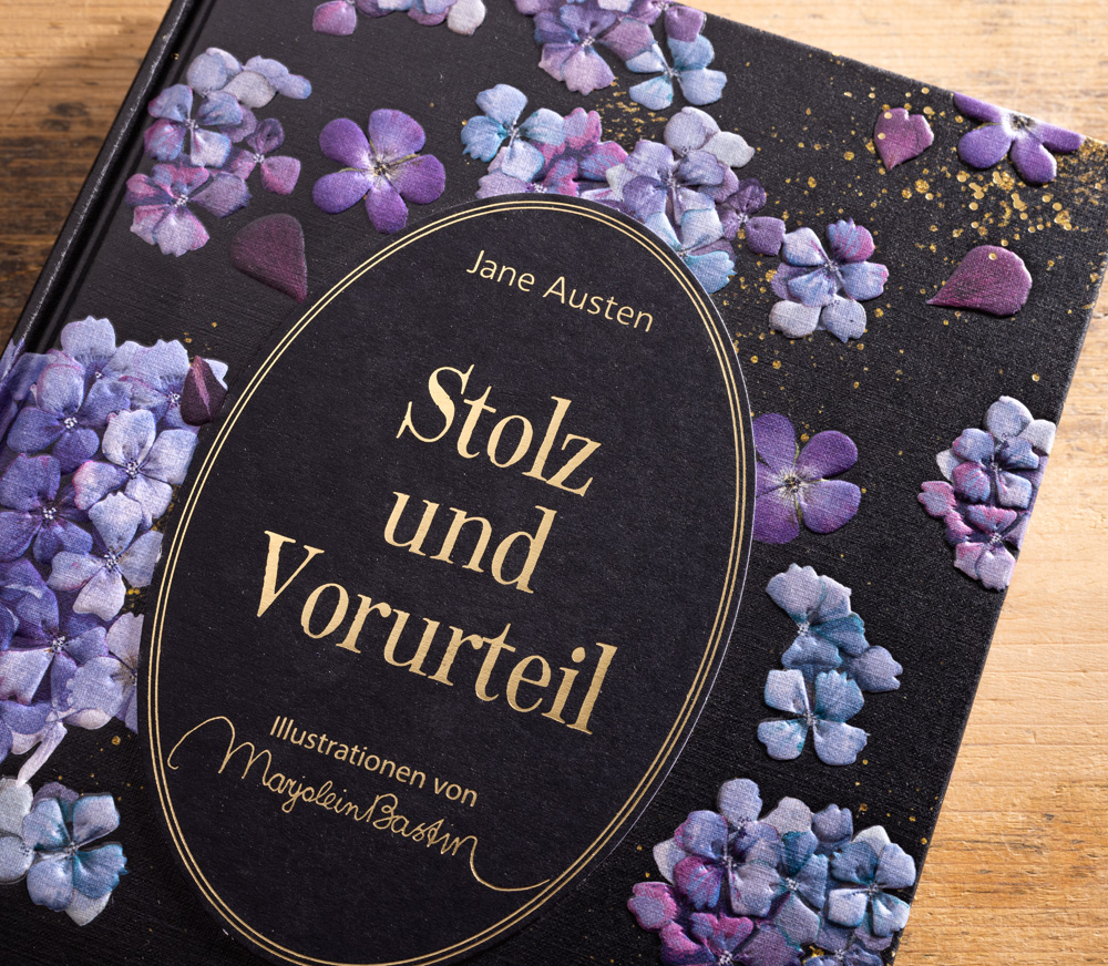 Nahaufnahme des Covers von Stolz und Vorurteil mit goldener Schrift und violettem Blütenrelief.