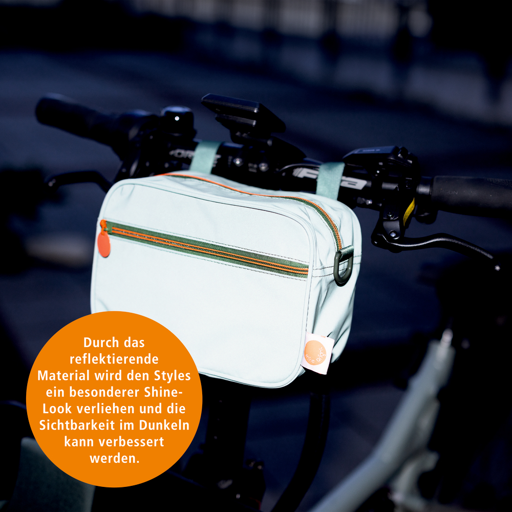 Reflektierende Lenkertasche mit orangefarbenem Reißverschluss an einem Fahrradlenker befestigt.