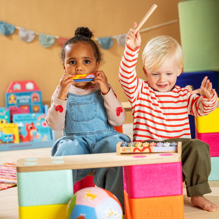 Kleine Kinder mit Mundharmonika und Xylophon lachen.